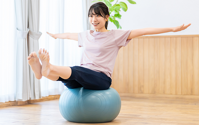 バランスボールに乗ってバランスをとる女性の画像