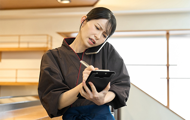 女性マネージャーがが電話をしながらスケジュール調整のメモを取っている画像