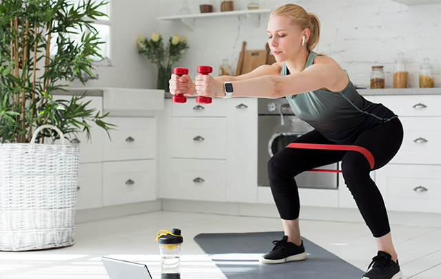 自宅のキッチンでスクワットをして身体を鍛えている健康な情勢の画像