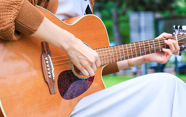 公園でギターを奏でる女性の画像