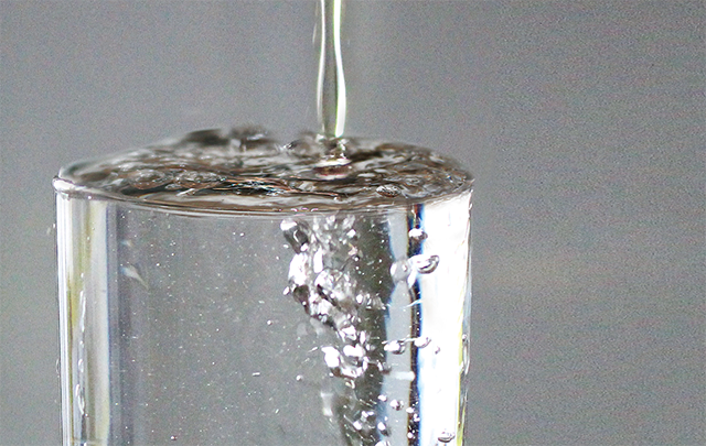 注がれてコップから溢れ出す水の画像