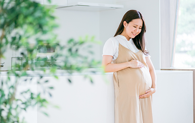 妊娠中の女性がキッチンで胎児の動きに喜びを感じているよユスの画像