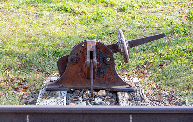 線路の脇に立つ方向を変える錆びついた線路のスイッチ（転轍器）の画像
