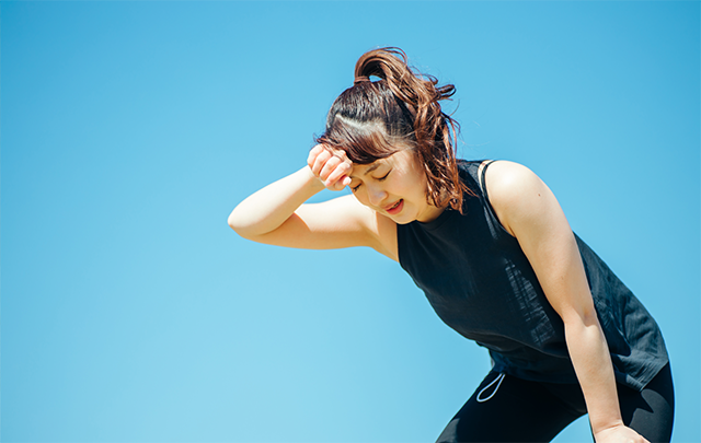青空の下、運動に疲れて果敢で休憩している若い女性の画像